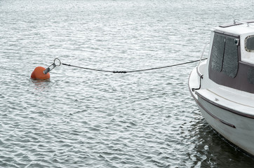 White boat in harbour with red buoy and rope