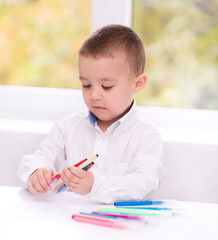 Little boy is writing using a pen