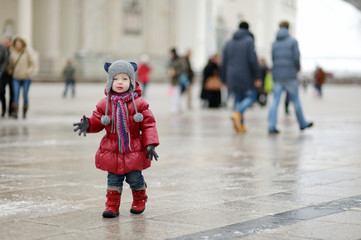 Toddler girl having fun on winter day in a city