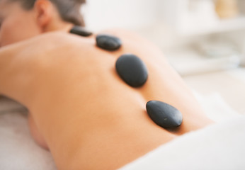 Closeup on young woman receiving hot stone massage. rear view