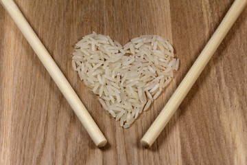 Rice grains in heart shape and chopsticks