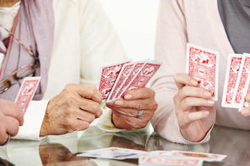 Hände von Senioren beim Karten spielen