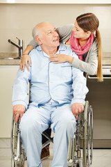 Enkelin umarmt Großvater im Rollstuhl