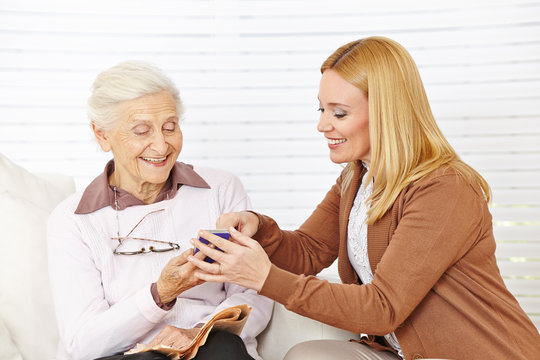Frau hilft Seniorin mit ihrem Smartphone
