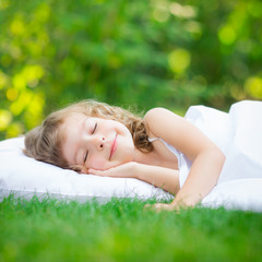 Naklejka na ściany i meble Child sleeping in spring garden