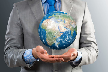businessman holds up a planet Earth