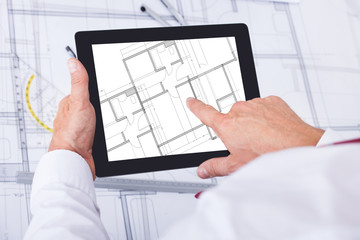 Male Architect Analyzing Blueprint Over Digital Tablet