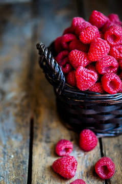 Raspberries in a basket on rustic wooden background