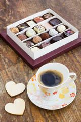 Assorted chocolate candies and cup of coffee on a wooden table