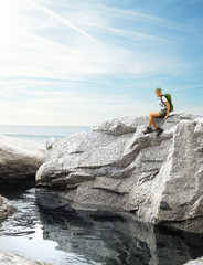 young traveler woman sitting on a rock near water