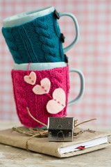 Two blue cups in pink and blue sweater on an old notebook
