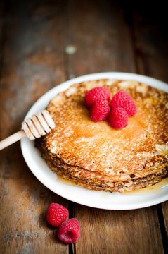Pancakes with maple syrup and raspberries on wooden background