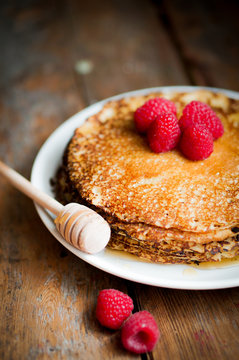 Pancakes with maple syrup and raspberries on wooden background