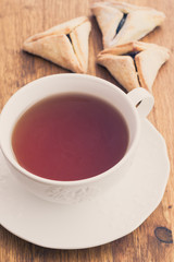 Hamantaschen cookies for Purim with cup of teaon a wooden surfac
