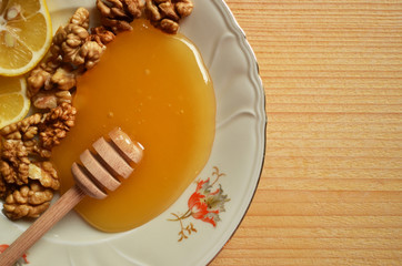 Honey with walnuts and lemon on wooden background