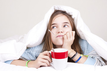 Sick young girl with thermometer in bed