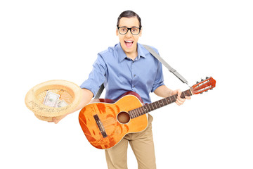Young male street performer with guitar collecting money
