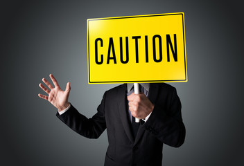Businessman holding a caution sign