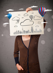 Woman holding a cardboard with cityscape in front of her head
