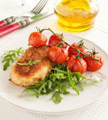 Chicken cutlet with grilled tomatoes and salad.
