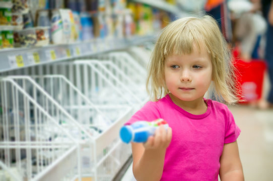 Adorable girl select milk products holding yogurt small bottle i