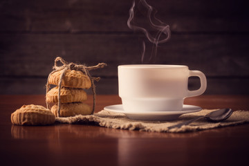 Cup of hot coffee with cookies on wooden background