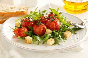 grilled tomatoes on a branch with a salad of arugula
