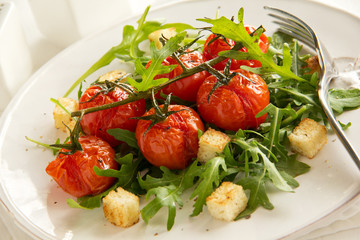 grilled tomatoes on a branch with a salad of arugula