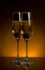 a pair of champagne flutes on dark golden light background