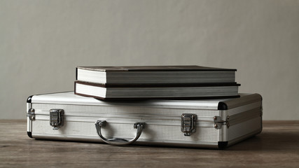 Books over aluminum suitcase on wooden table