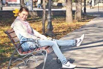 girl in jeans sitting on a bench in the park