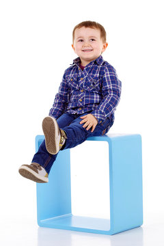 petit garçon assis sur un cube bleu