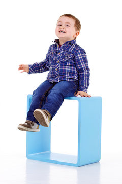 petit garçon assis sur un cube bleu bleu