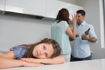 Obraz na płótnie Canvas Sad girl while parents quarreling in kitchen