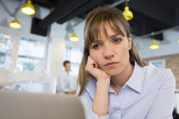 Depressed businesswoman in office behind her laptop