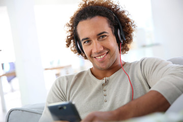 Cheerful attractive man listening to music © goodluz