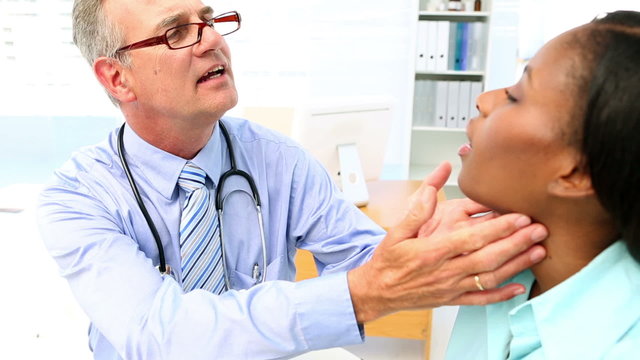 Doctor checking throat glands of his patient