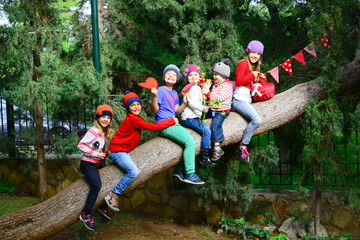Group of happy kids sitting on a large tree trunk © PhotoeffectbyMarcha