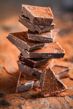 stack of dark chocolate pieces and cocoa powder