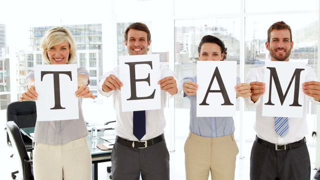 Business people holding up pages spelling out team