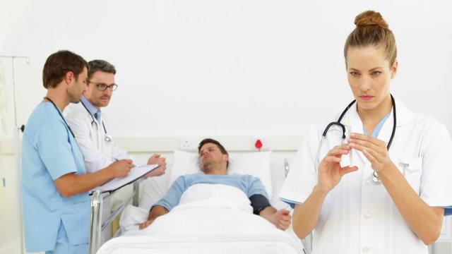 Doctors speaking with patient while nurse prepares injection