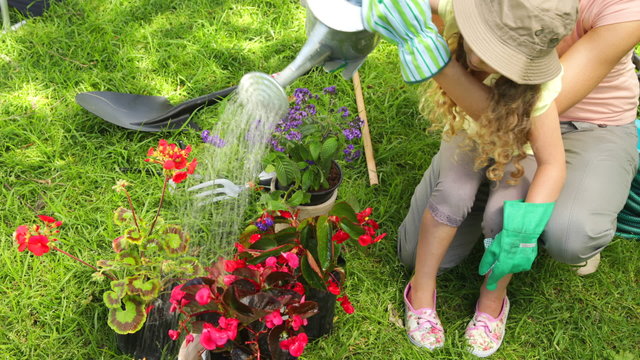 Cute little girl watering flowers with her mother