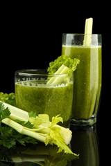 Glasses of green vegetable juice and celery isolated on black