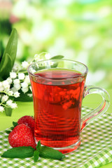 Delicious strawberry tea on table on bright background