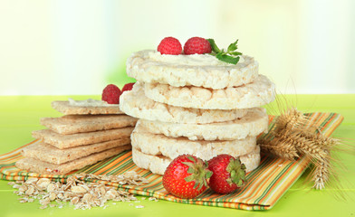Tasty crispbread with berries, on green table