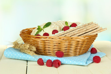 Tasty crispbread with berries in wicker basket, on white table