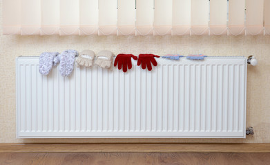 Knitted gloves drying on heating radiator