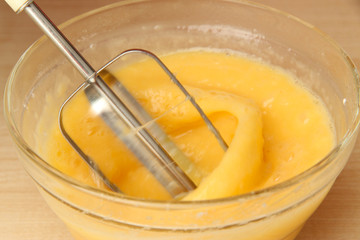 Cooking, whipping eggs with electric whisk in bowl, close up