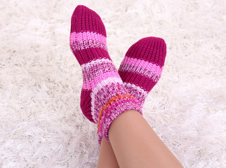Female legs in colorful socks on white carpet background