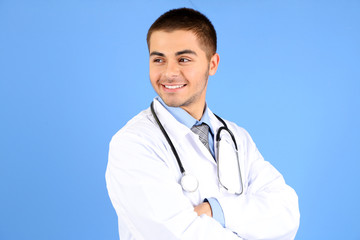 Male Doctor standing with folder, on blue background